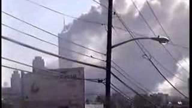 View from NJ, towers burning, people gathered watching and...